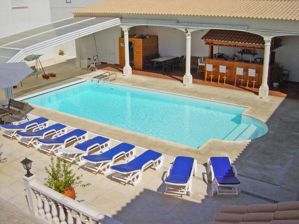 a large swimming pool with chairs and a table at Casas da Vila in Vimieiro
