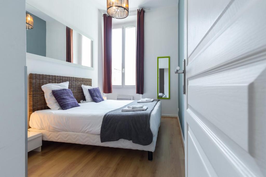 a small bedroom with a bed and a mirror at Florella Marceau Apartment in Cannes