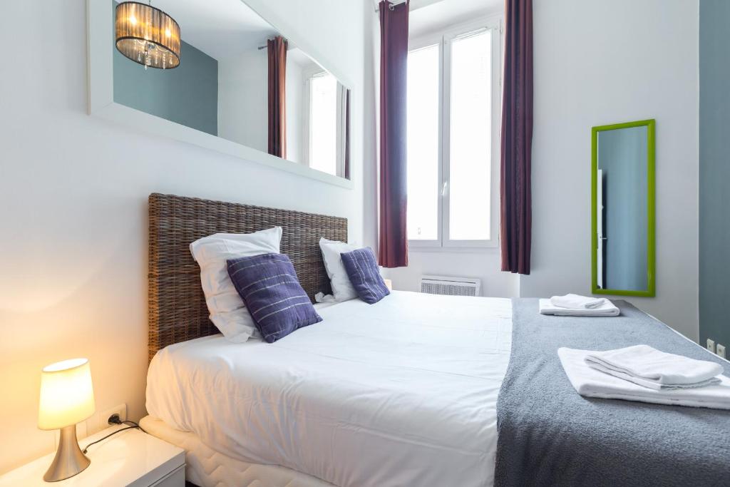 a bedroom with a large white bed with blue pillows at Florella Marceau Apartment in Cannes