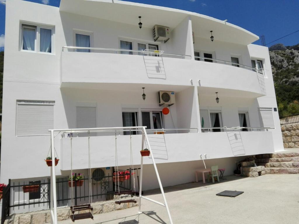 a white house with a balcony and a staircase at Apartmani Vukmanovic in Čanj