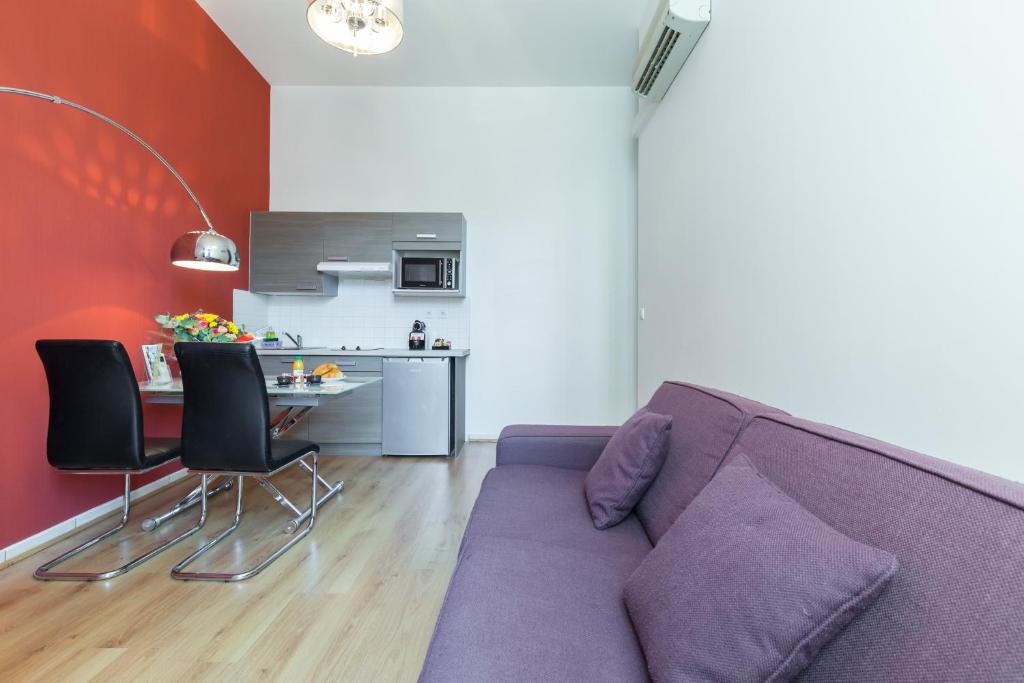 a living room with a purple couch and a table at Florella Marceau Apartment in Cannes