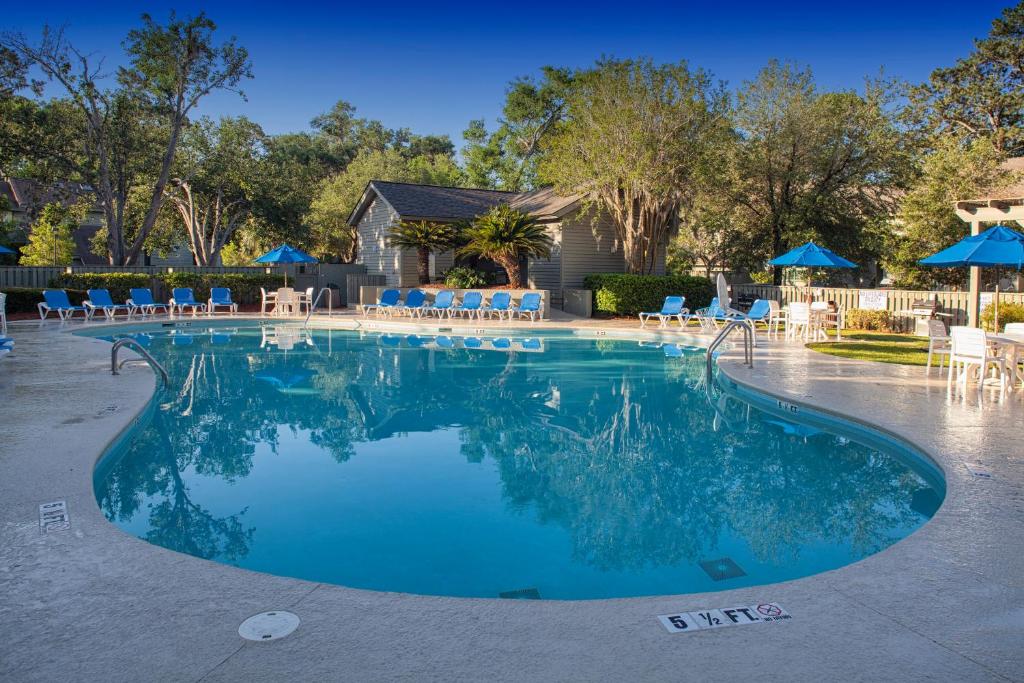 a swimming pool with blue chairs and umbrellas at Shipyard by Spinnaker Resorts in Hilton Head Island