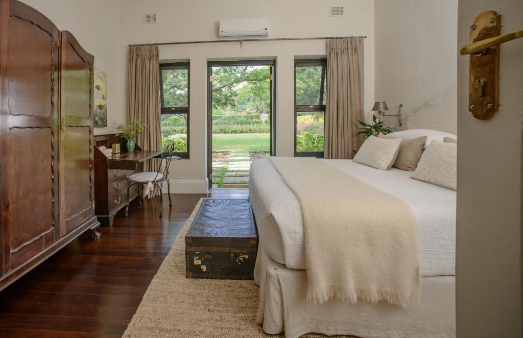 una camera con letto, scrivania e finestre di Torburnlea Homestead Luxury Accommodation a Nelspruit