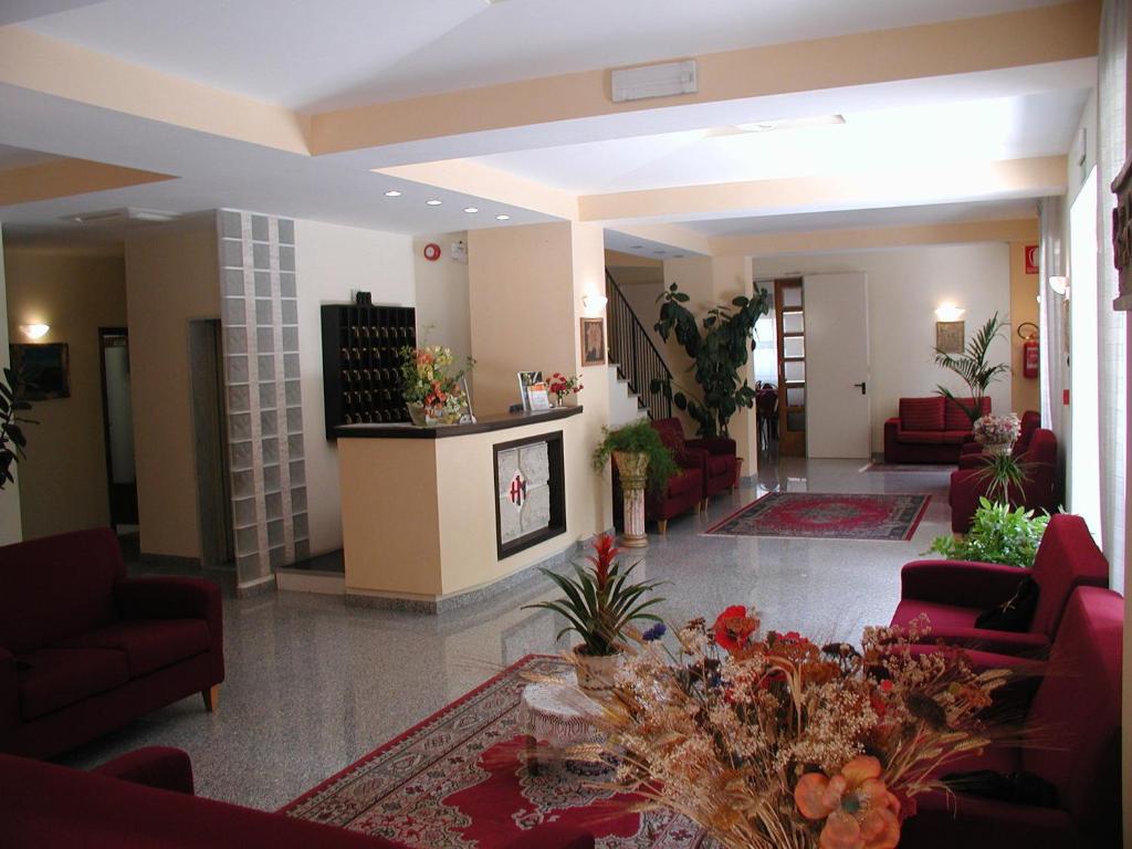 a lobby with red chairs and a table with flowers at Hotel Marystella in Chianciano Terme