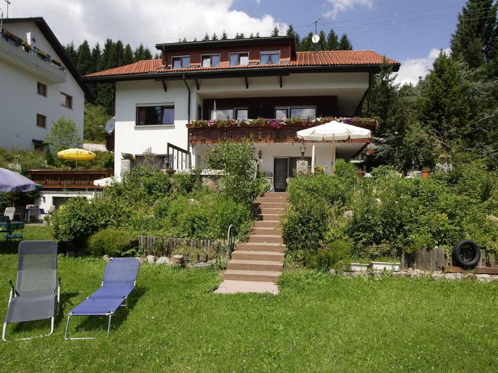 dom z dwoma krzesłami i parasolką w trawie w obiekcie Haus Bernhardt-Fromm w mieście St. Blasien