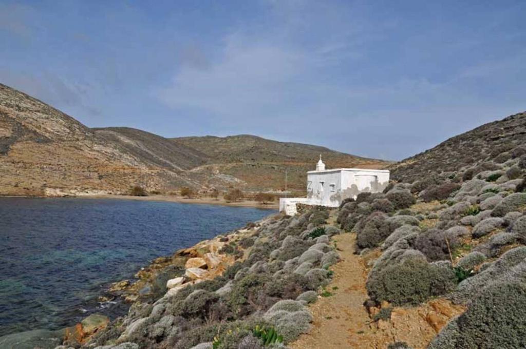 a small white building on the side of a body of water at panormos studio in Panormos