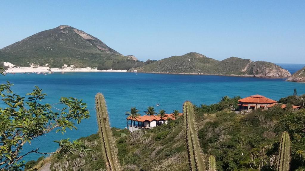 a view of a beach with mountains in the background at Suítes Independentes Praia dos Anjos in Arraial do Cabo