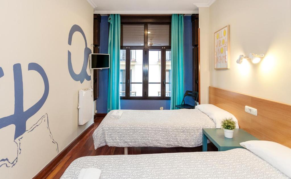 Habitación con 3 camas y cortinas azules. en Pensión Goiko, en San Sebastián