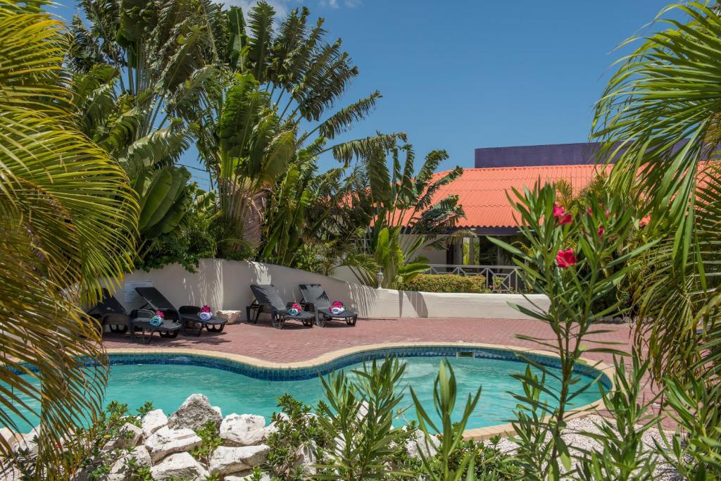 una piscina con sillas y palmeras en un patio en Blue Marlin Apartments, en Willemstad