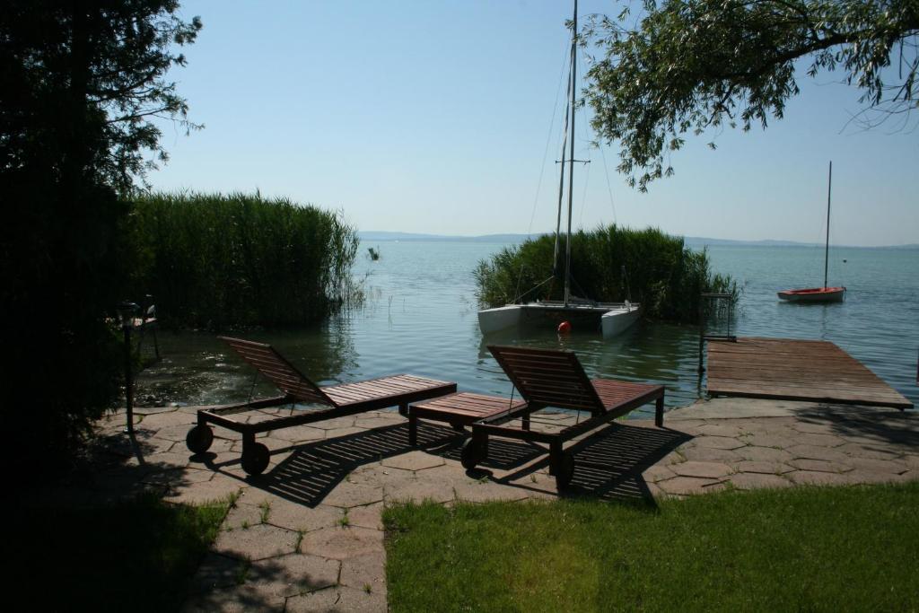 2 chaises et une table de pique-nique à côté de l'eau dans l'établissement Beach house, à Zánka