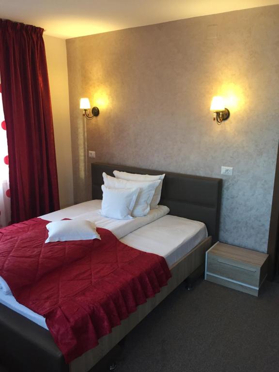 una camera d'albergo con un letto con una coperta rossa di Pensiunea Flora a Piatra Neamţ