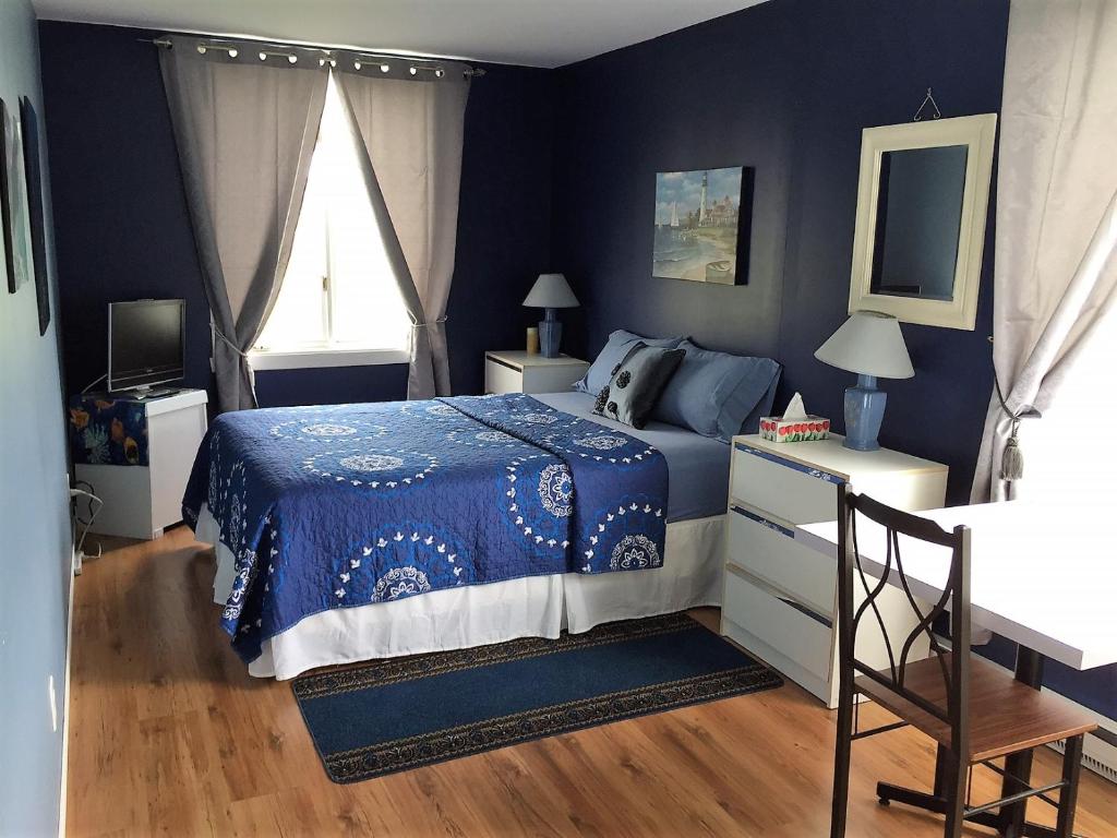 a blue bedroom with a bed and a window at Gîte du Moulin in L'Isle-aux-Coudres