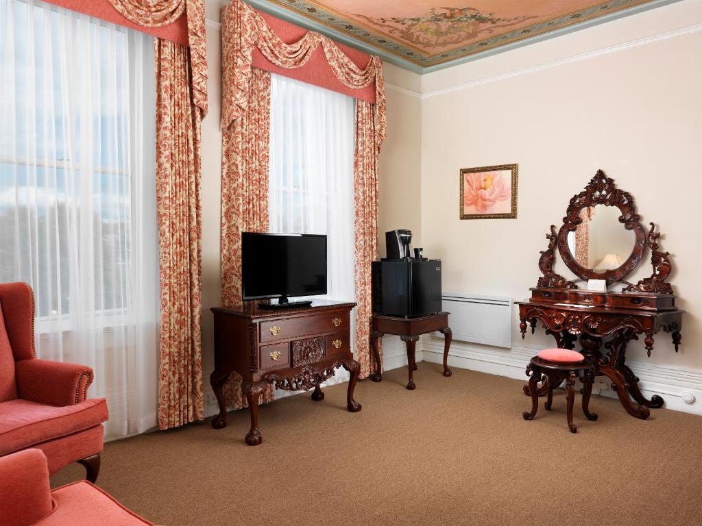 a living room with a tv and a mirror at Pendray Inn and Tea House in Victoria