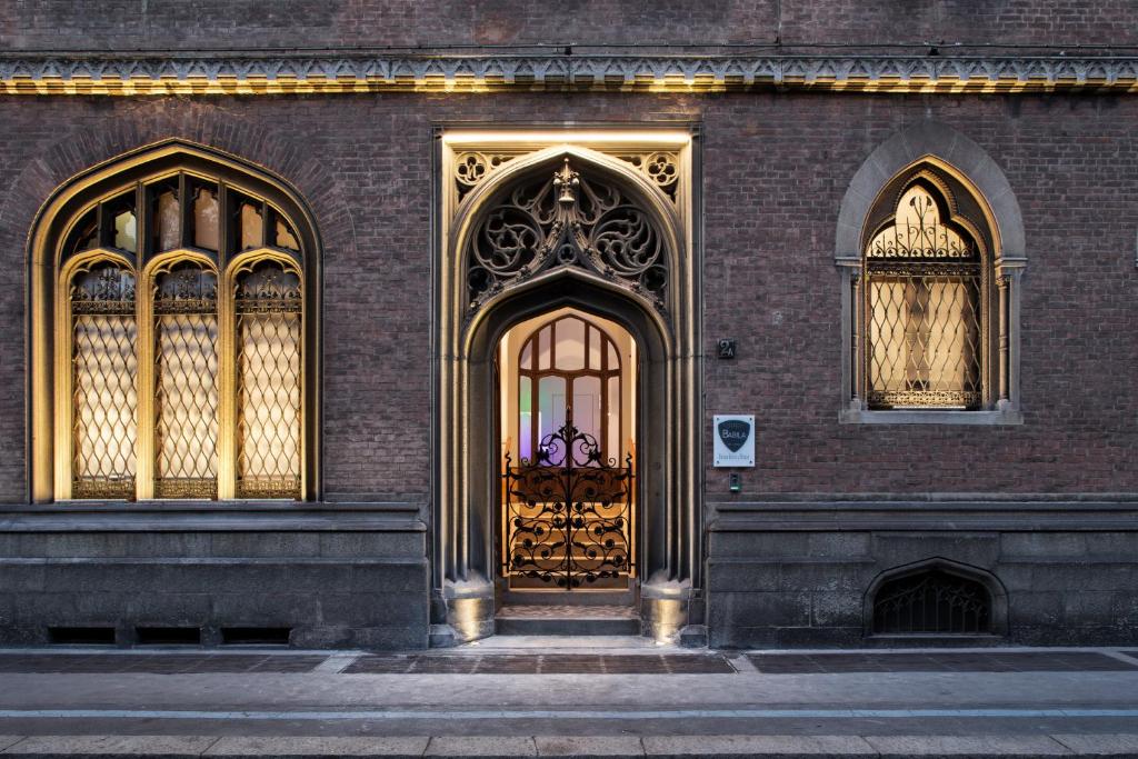 a brown brick building with a gold door and two windows at Babila Hostel & Bistrot in Milan