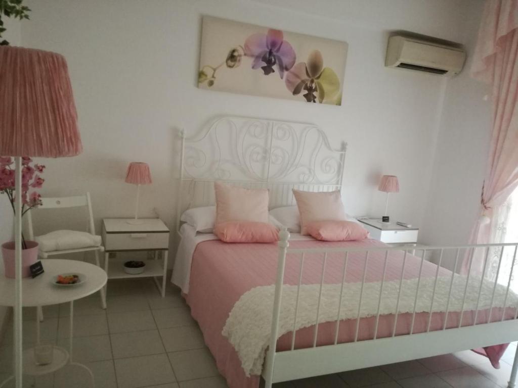 um quarto com uma cama branca e almofadas cor-de-rosa em B&B La Casa di Isabella Loreto em Loreto