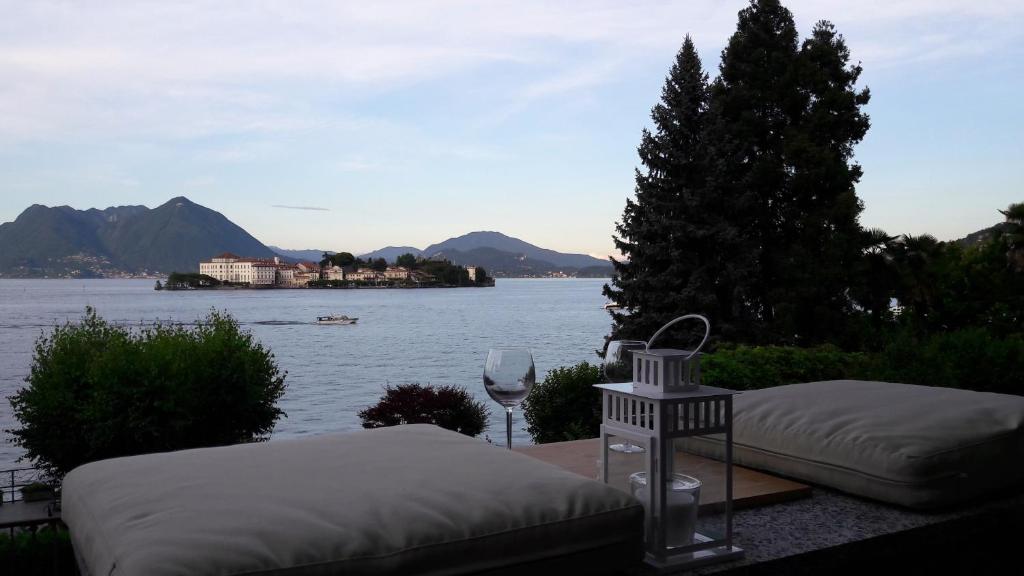 Una vista de un lago con dos camas y una copa de vino. en Villa la Serra, en Baveno