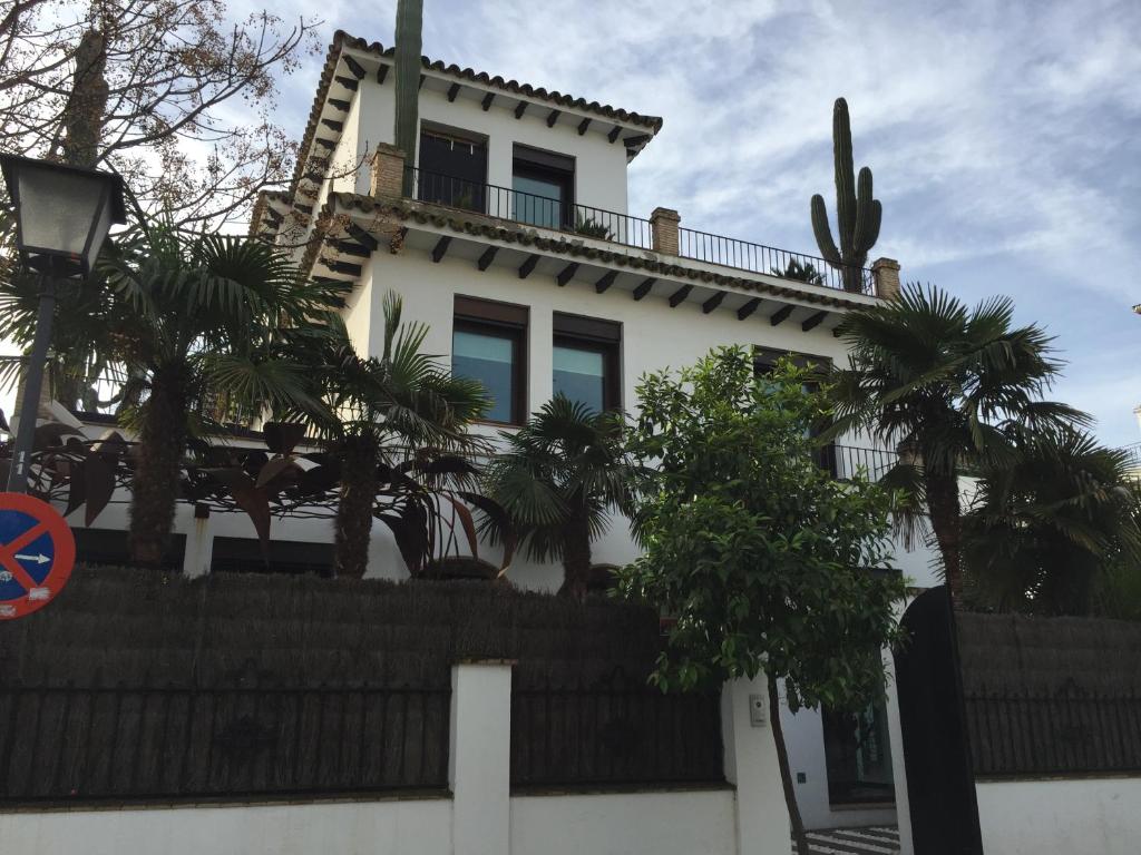 セビリアにあるla casa de las pergolasの椰子の木と柵のある白い家