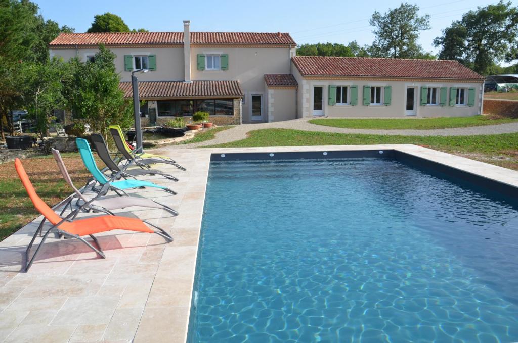 a swimming pool with chairs and a house at La Ferme Des Vergnes in Gabillou