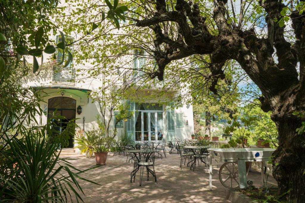 um pátio com mesas e cadeiras debaixo de uma árvore em La Bellaudiere em Grasse