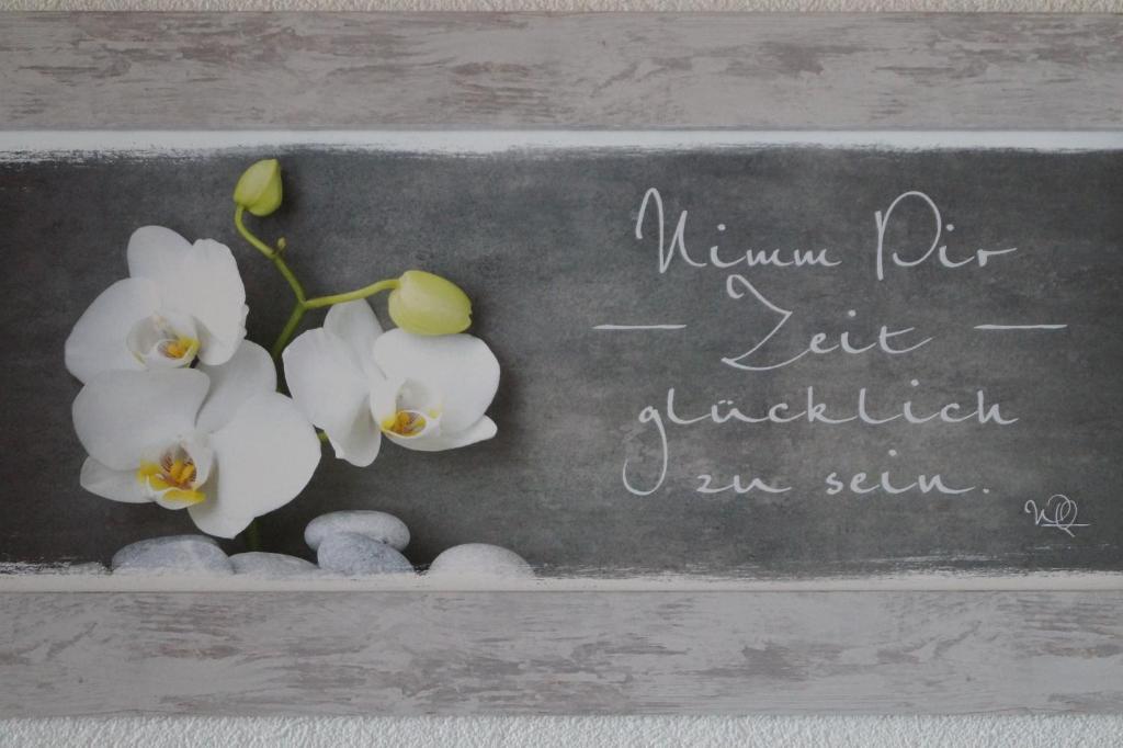 a chalkboard with white orchid flowers and rocks at Hotel "Wilder Mann" in Linz