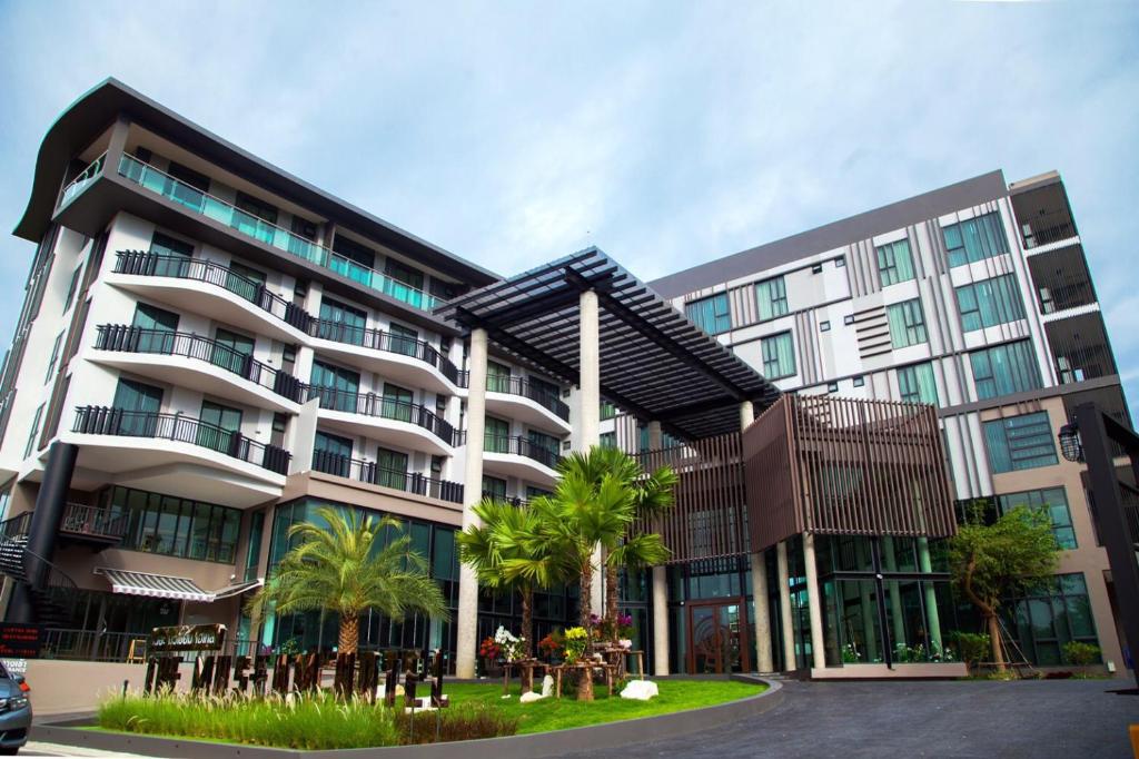 a large building with palm trees in front of it at The Museum Hotel in Nakhon Pathom
