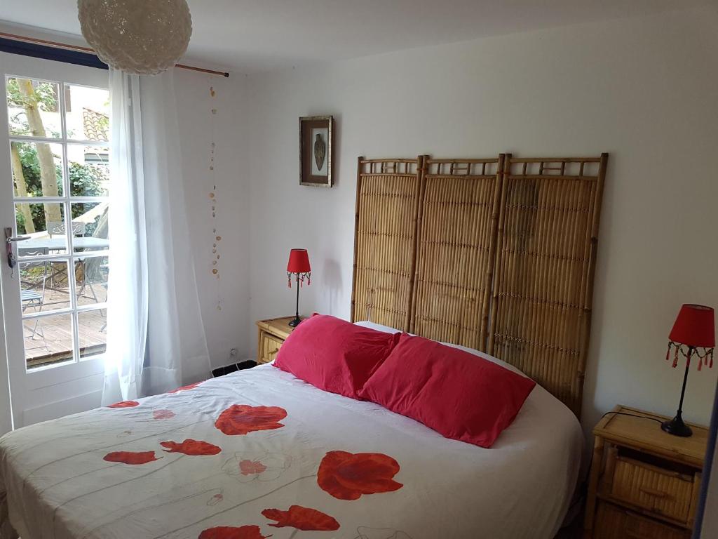 a bedroom with a bed with red sheets and a window at Villa Akwaba in Pyla-sur-Mer
