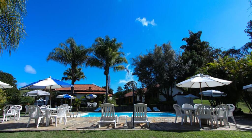 um grupo de cadeiras brancas e guarda-sóis ao lado de uma piscina em Fazenda Alvorada em Cunha