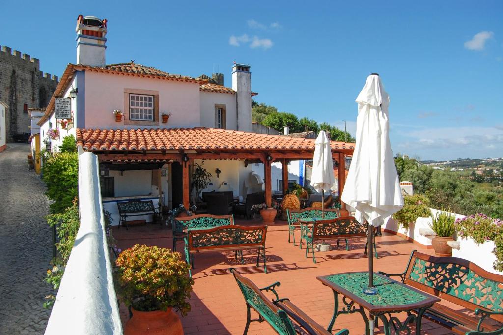 an outdoor patio with tables and chairs and an umbrella at Casa Do Relogio in Óbidos