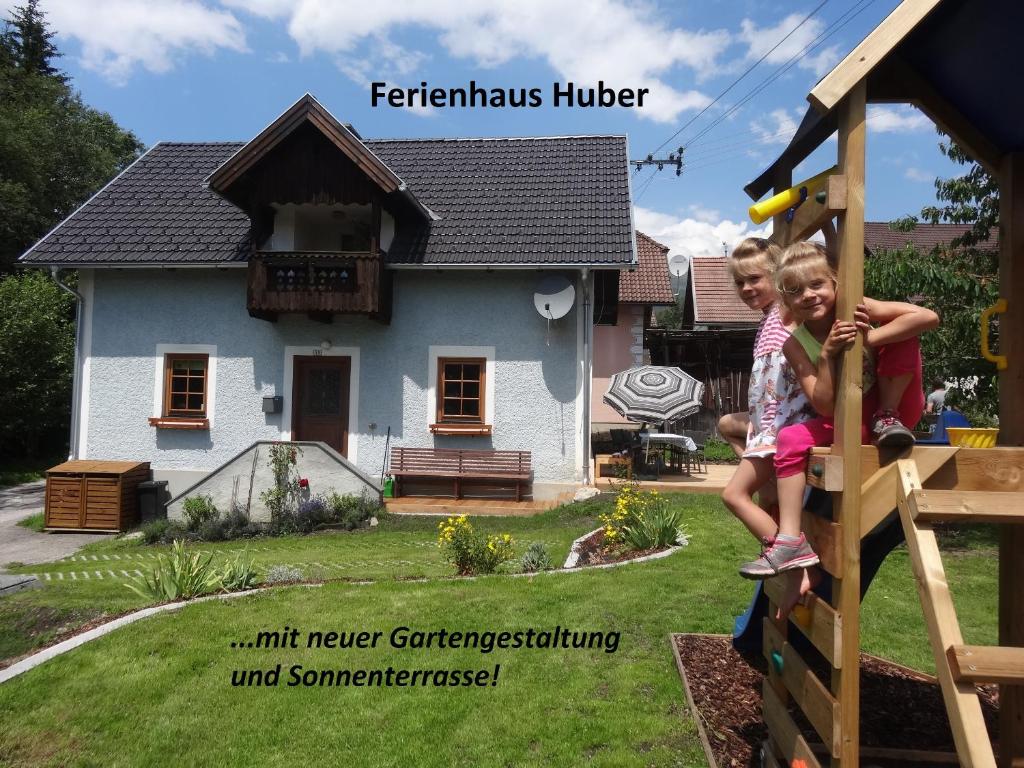 Due ragazze che giocano su uno scivolo davanti a una casa di Ferienhaus Huber a Mariapfarr