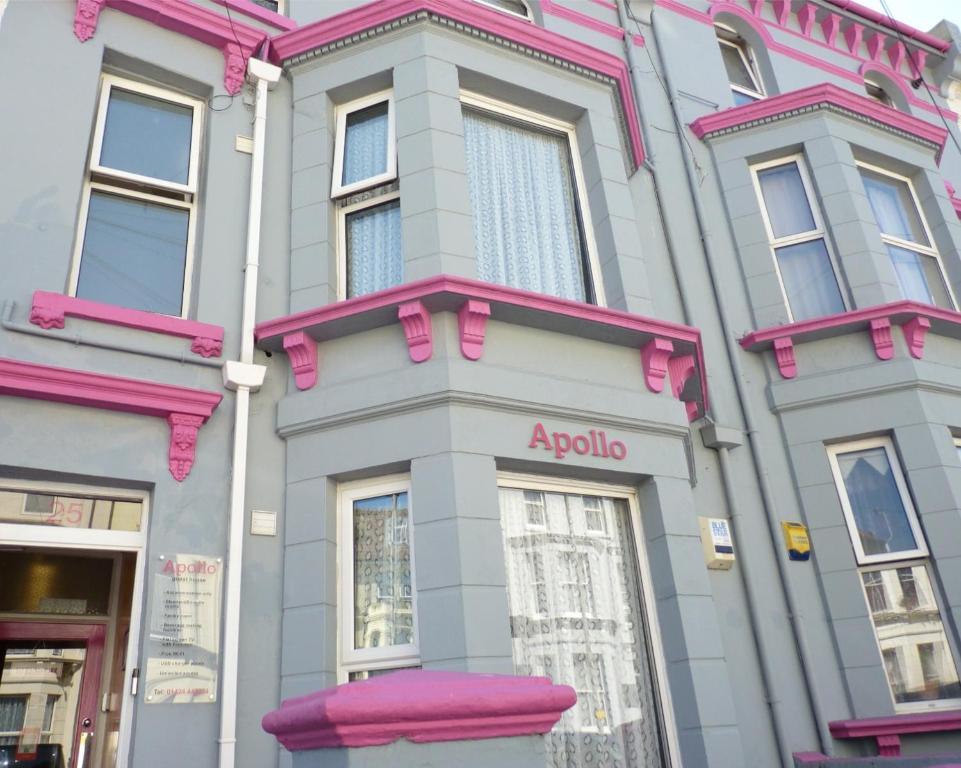 un edificio rosa y gris con un cartel de aania en él en Apollo Guest House en Hastings