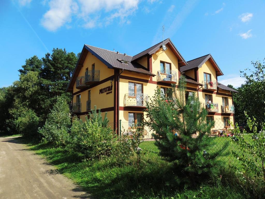 a large house on a dirt road next to a tree at Pokoje gościnne Przystań in Dębki