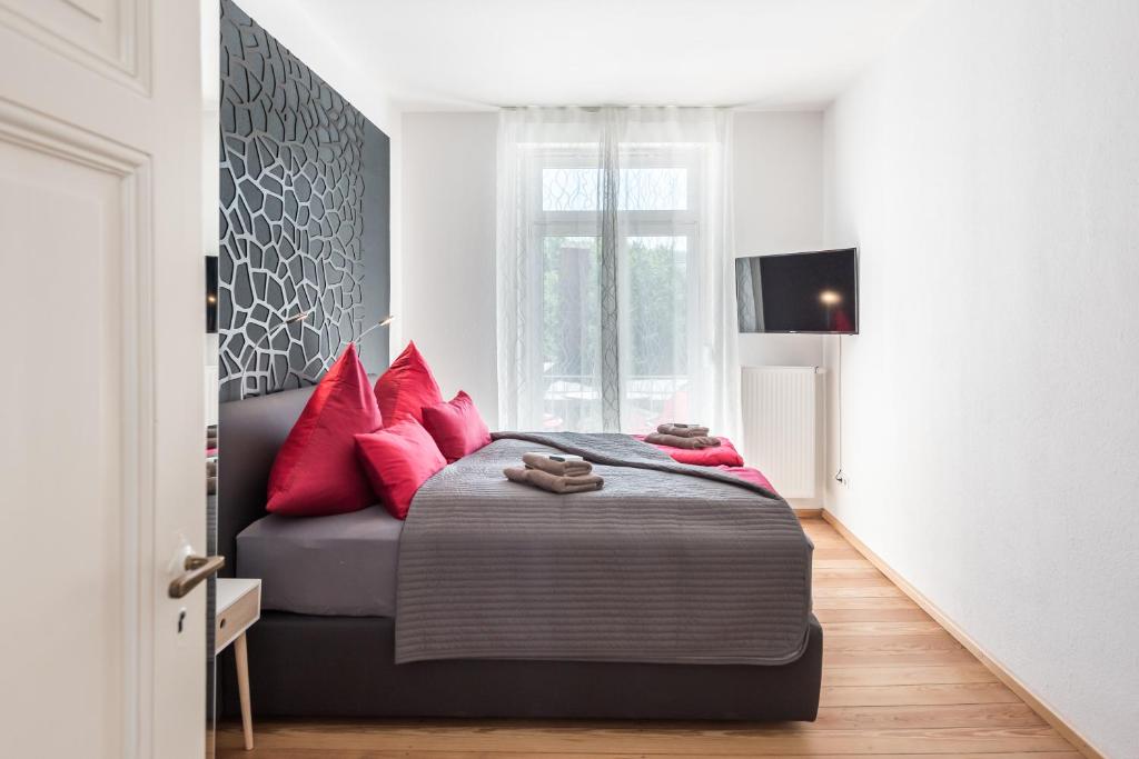 sypialnia z łóżkiem z czerwonymi poduszkami i kanapą w obiekcie Family-Apartments Freiburg we Fryburgu Bryzgowijskim