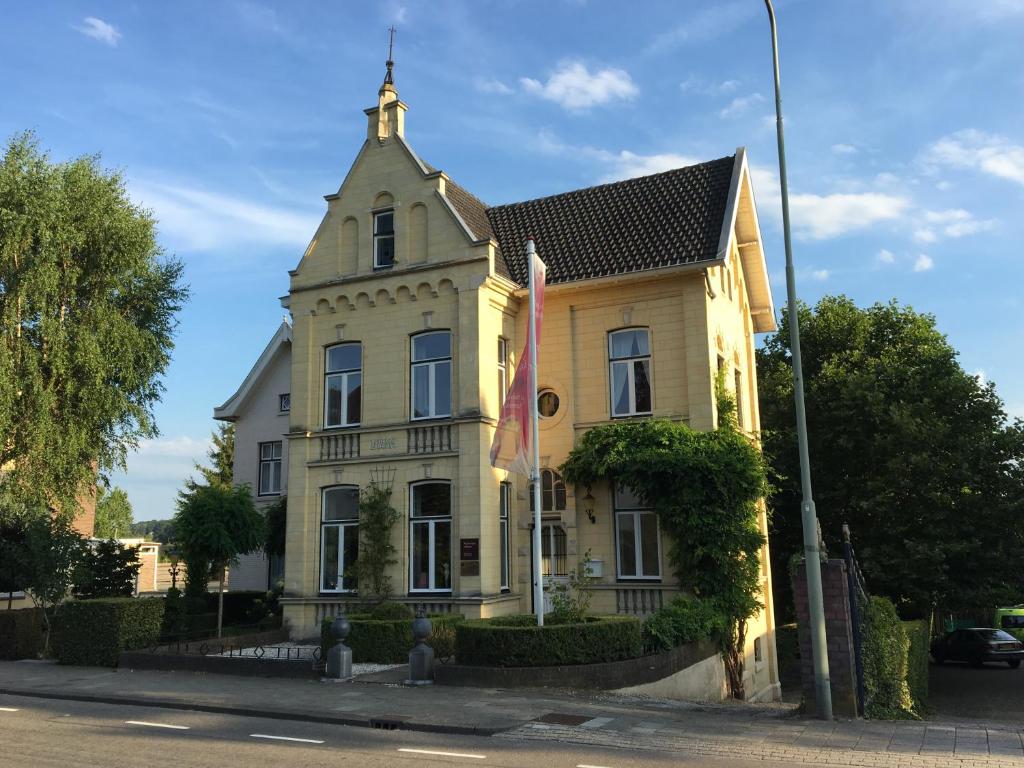 een geel huis met een toren op een straat bij Vakantie appartement Villa Diana in Valkenburg