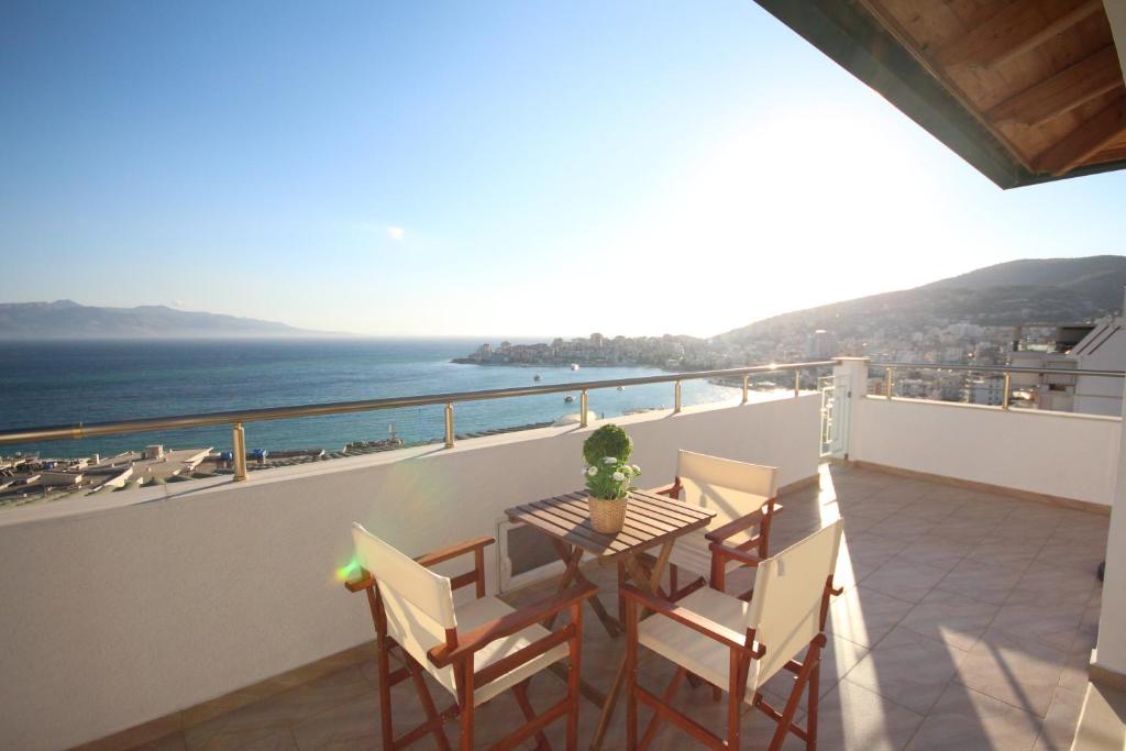 a balcony with a table and chairs and the ocean at Nefeli Apartments in Sarandë