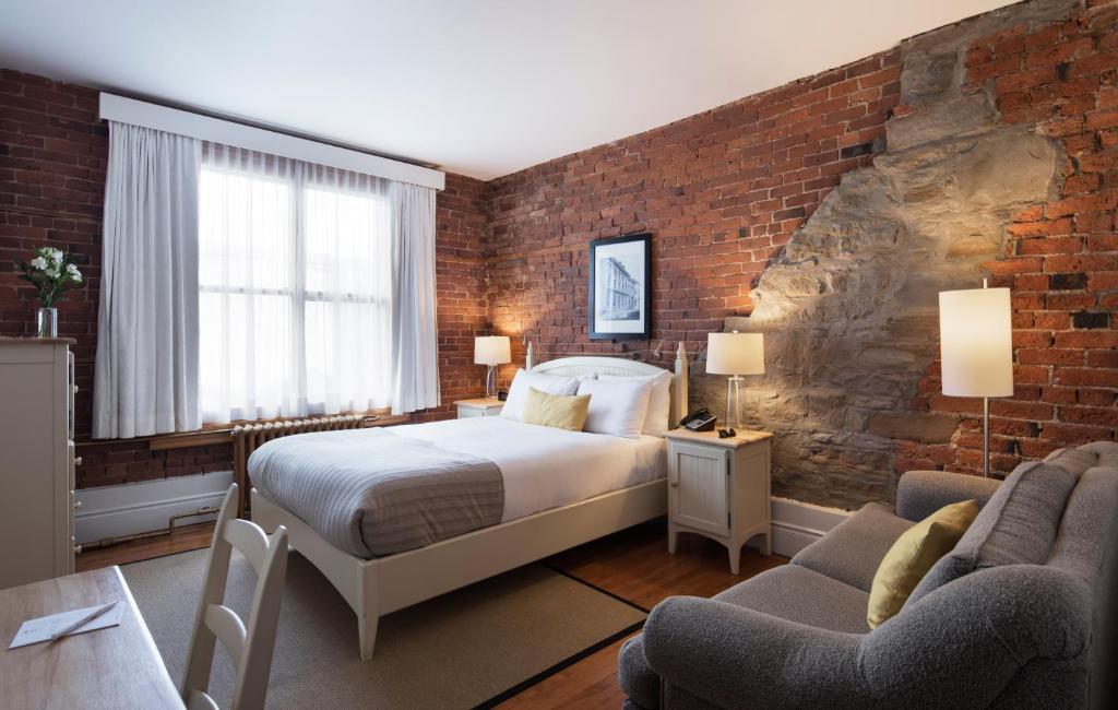 um quarto com uma cama e uma parede de tijolos em Auberge Saint-Pierre em Quebeque