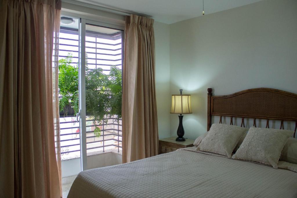 a bedroom with a bed and a large window at Villago Residences in Santo Domingo