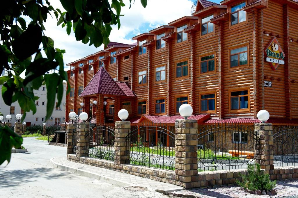 un gran edificio de madera con una valla delante en Belka-Hotel, en Yuzhno-Sakhalinsk
