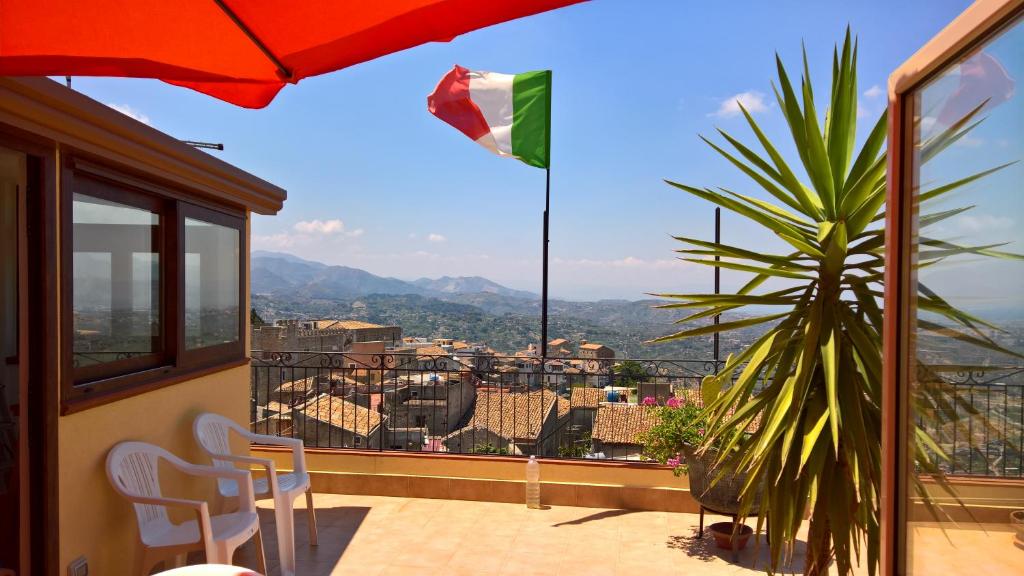 balcón con sombrilla y vistas a la ciudad en B&b La Giara, en Roccavaldina