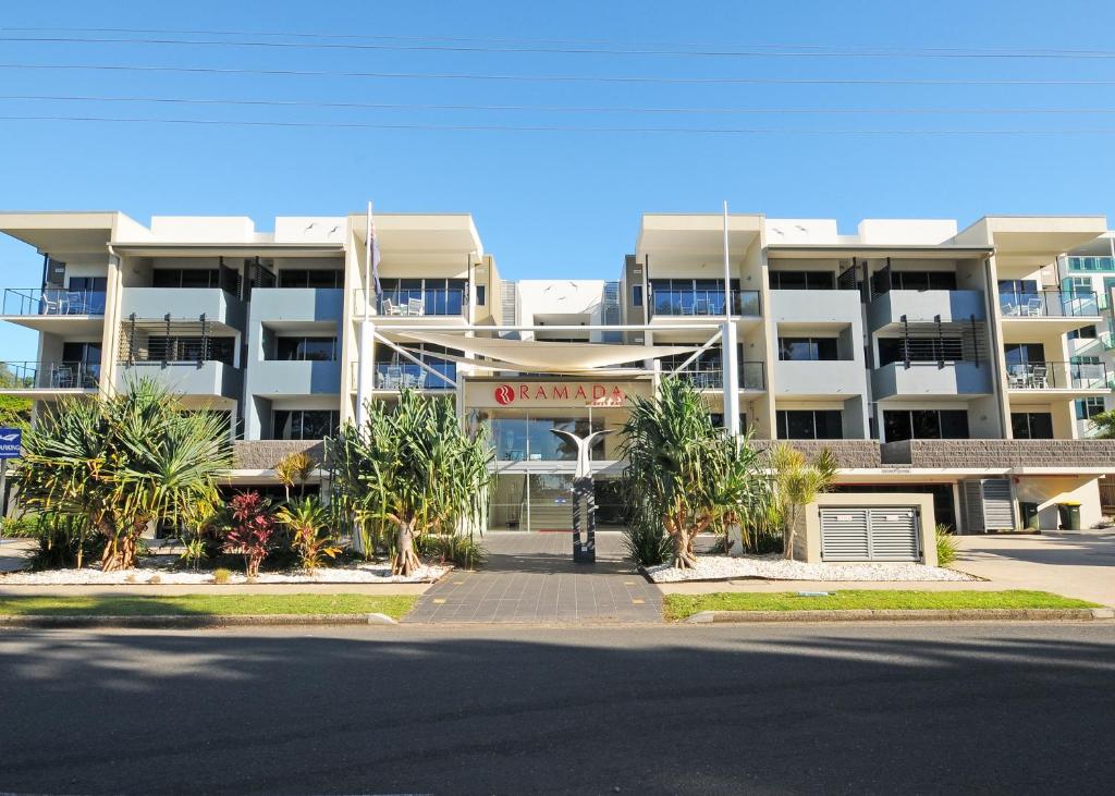 Ramada by Wyndham Hervey Bay في خليج هيرفي: عمارة سكنية كبيرة امامها نخيل