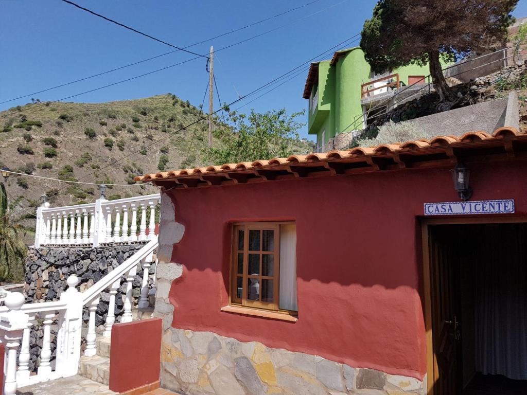 una casa roja y blanca con una colina al fondo en Casa Rural Vicente, en Vallehermoso