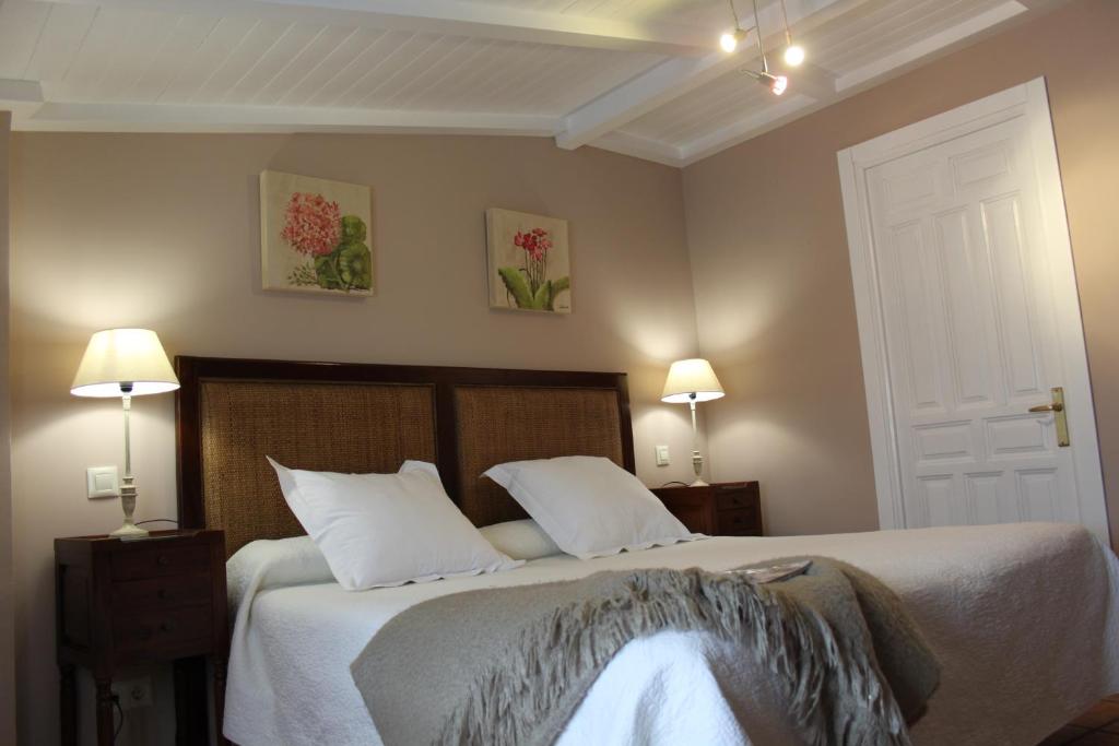1 dormitorio con 1 cama con sábanas blancas y 2 lámparas en La Casona de Lucía, en Sigüenza