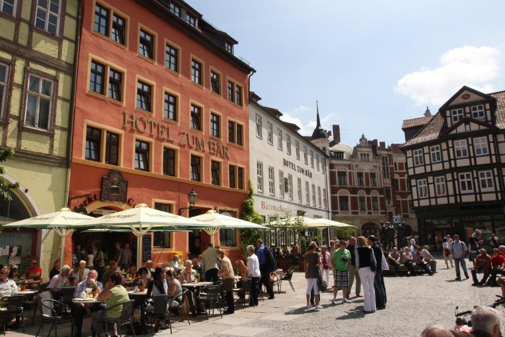 a group of people standing around in a street with buildings at Hotel Zum Bär in Quedlinburg