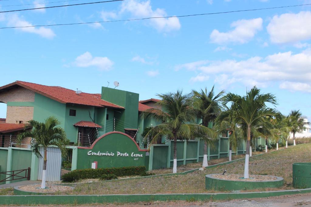 a green building with palm trees in front of it at Excelente Casa Duplex in Aquiraz