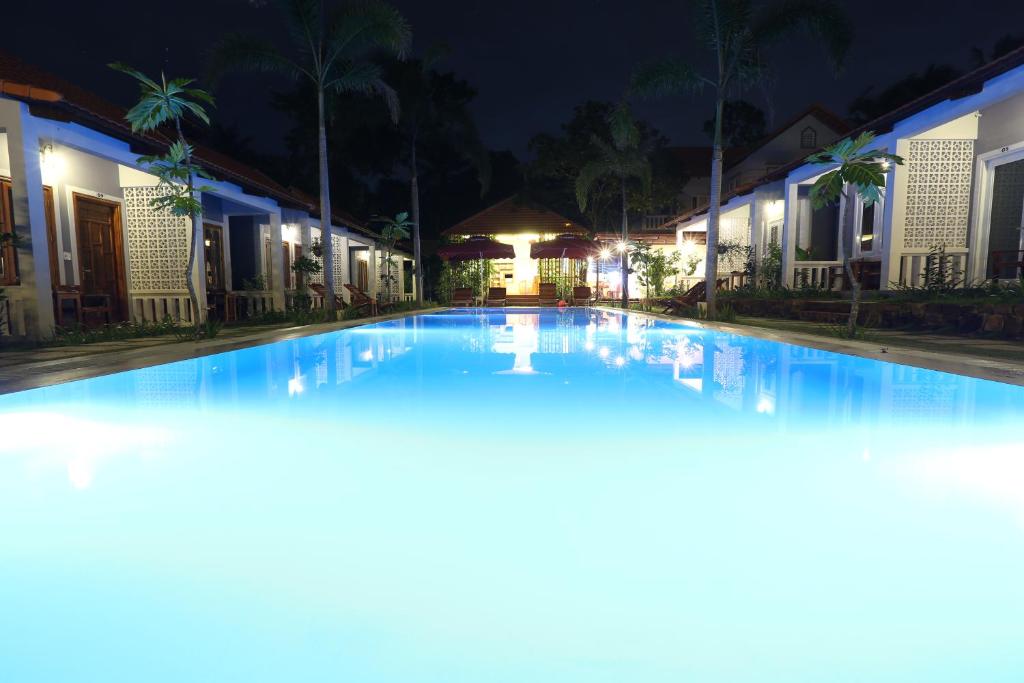 una grande piscina notturna con edifici di Gecko House a Phu Quoc