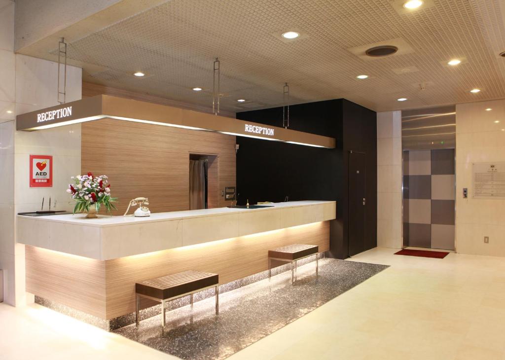 a hotel lobby with a reception desk and two benches at Saku Grand Hotel in Saku