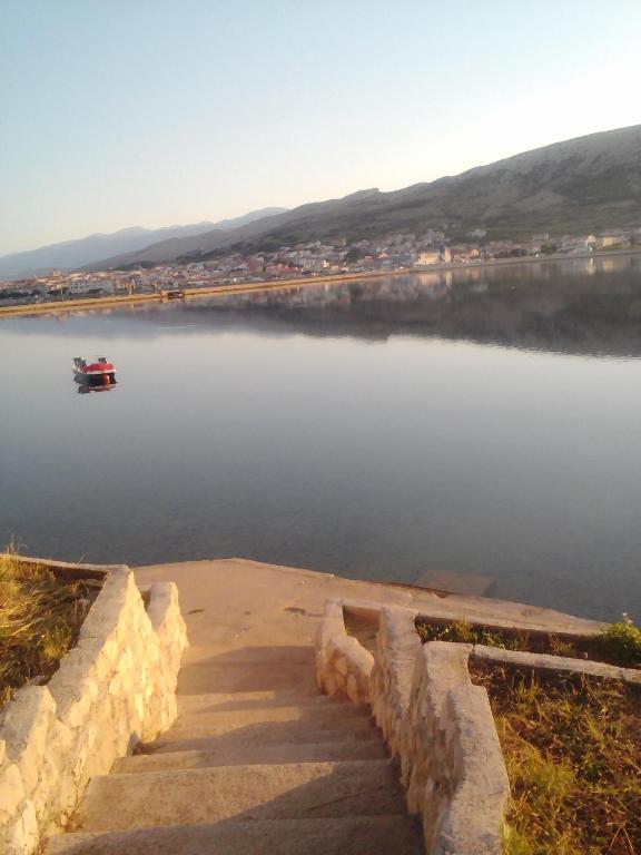 a small boat on a lake with a boat in the water at Apartments Boki in Pag