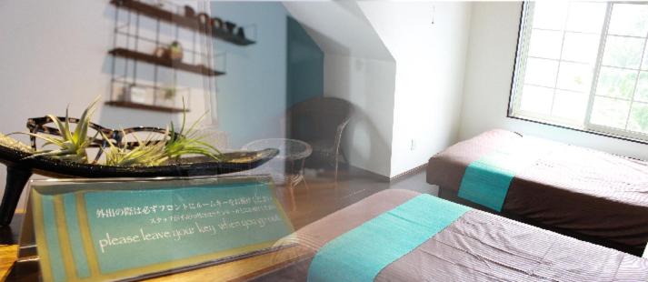 恩納村にある南国ロッジBooyaのベッド1台とテーブルの上に看板が備わる客室です。