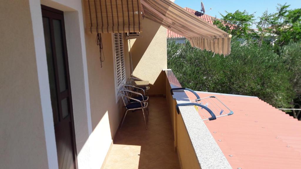 a balcony with a table and chairs on a house at Nora Apartments in Povljana