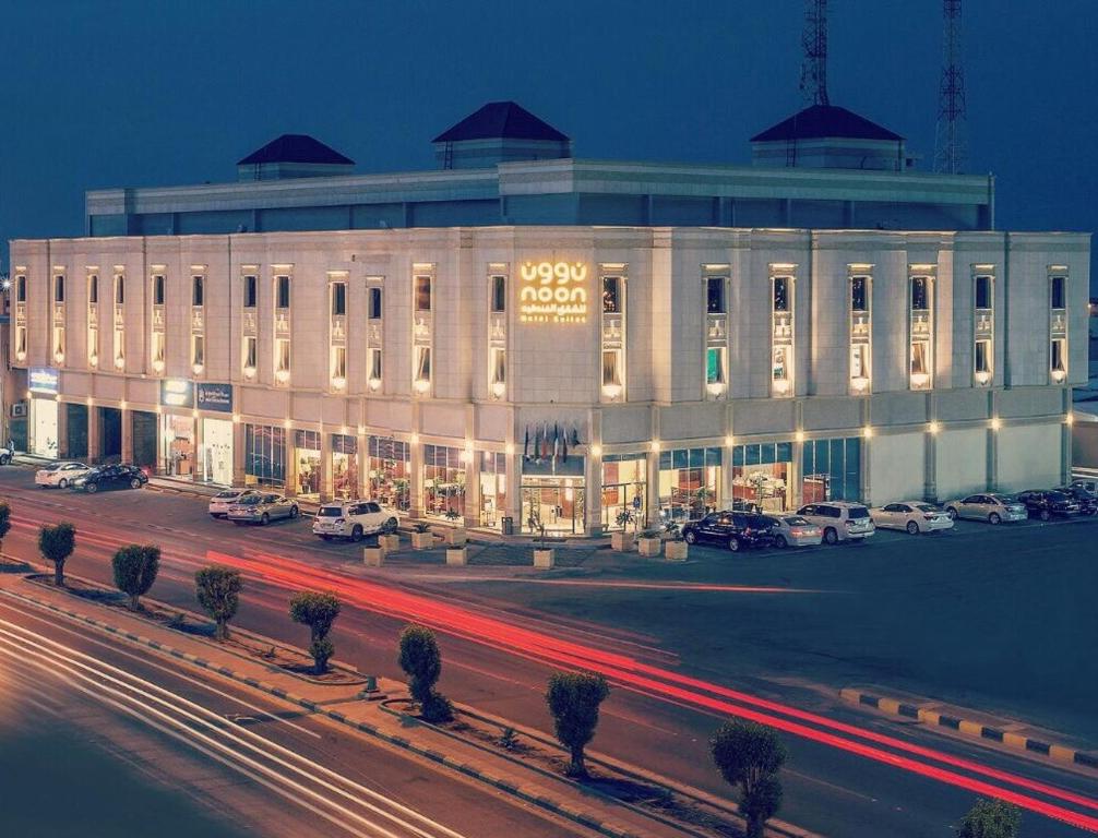 un gran edificio blanco con coches aparcados en un aparcamiento en Noon Hotel Suites, en Al Khafji