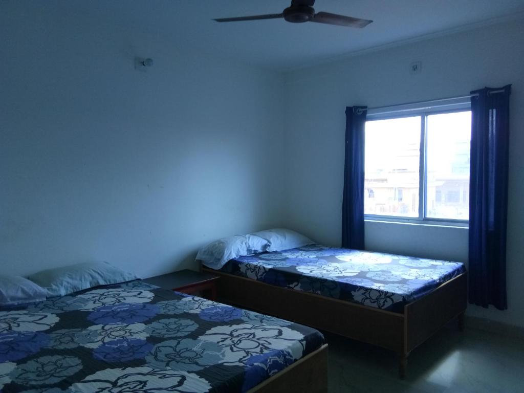Duas camas num quarto com uma janela em Bodhgaya Guest House em Bodh Gaya